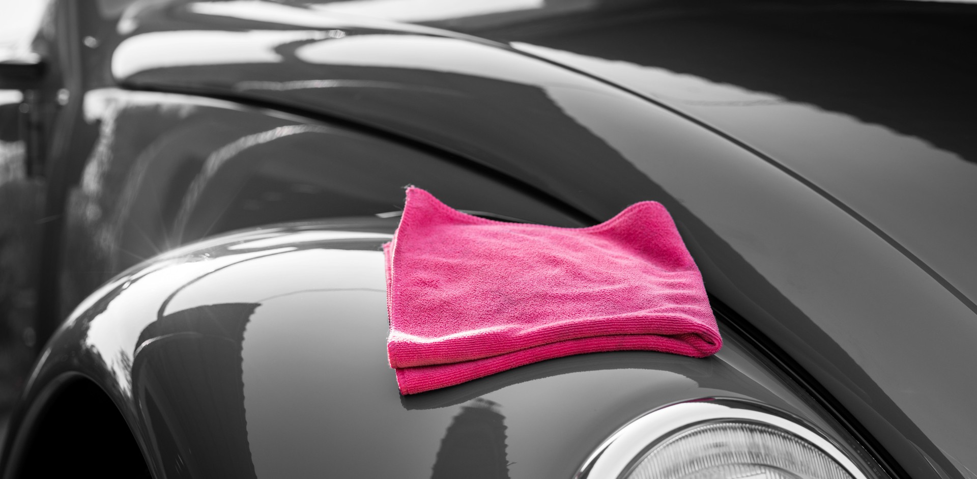 Shiny and clean black car with a pink rag on top
